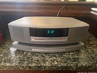 Front view of Bose Wave Music System III with SoundTouch pedestal showing digital display at 3:12 and CD slot