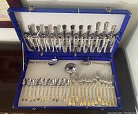 Full view of open blue box showing all flatware pieces secured in straps.