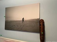 Frameless canvas print of surfer walking on a beach with a surfboard, sepia toned image.