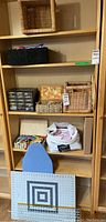 Wooden shelving unit with multiple woven and plastic baskets containing sewing supplies including fabric and thread