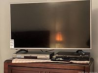 Sharp 40-inch LED LCD TV on top of two silver and black electronic devices including a DVD player.