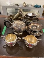 Lot items arranged on table showing teapot, sugar bowls, trays, candy dishes and vase.