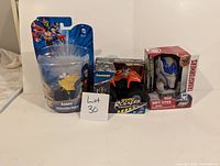 Overview photo of the three boxed toys: Robin collectible figure, Kawasaki Road Rocket toy, and Transformers Soft Lite figure.