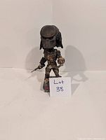 Front view of Predator 2 bobblehead figure on white background with lot sign in front