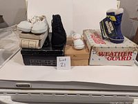 Full view of lot showing five pairs of shoes and boots on and around boxes.