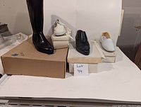 Four brand new vintage shoes and boots displayed on top of original brown and white shoe boxes with visible box wear and damage.