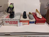 Four pairs of shoes on top of their original boxes, brand new but boxes show storage wear.