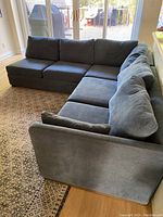 Front view of blue L-shaped sectional sofa on area rug with sliding glass doors in background