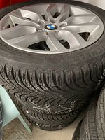 Front view of silver alloy rim with BMW center cap mounted on tire