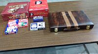 Photo showing multiple boxed games including Yahtzee, Scattergories, Uno, Star 80, and a closed wooden backgammon case on a table.