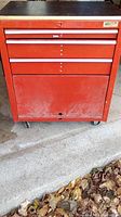 Full frontal image showing red metal tool chest with three drawers stacked above a larger compartment base on wheels.