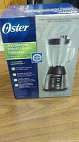 Front box view showing Oster logo, product image, and Fusion Food Processor Blender branding with features and usage info.