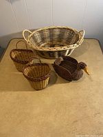 All five assorted wicker baskets including a large oval basket, two small rounded baskets, one small rectangular basket, and a duck-shaped basket.