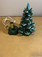 Front angle of ceramic Christmas tree and matching base with cord and bulb visible