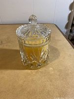 Crystal jar candle with lid on, showing full jar and lid design and yellow candle inside.