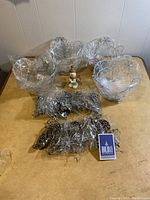 Four silver decorative wire baskets, one snowman figurine, and multiple silver ornaments on a table