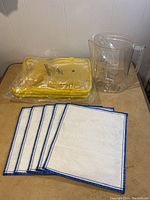 Photo showing 5 placemats beside a yellow picnic set carrying case and Brita jug