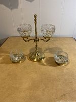Full view of the brass holder with two mounted crystal bowls and two separate crystal bowls with brass bases on a table surface.