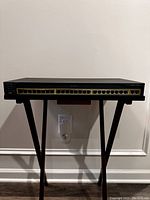 Front view of Cisco Catalyst 2950 switch showing 24 Ethernet ports and 1 Gigabit port, powered off and placed on a stand.