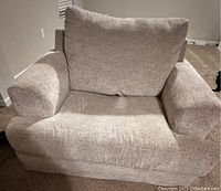 Front and angled view of oversized chair showing plush cushioned arms, back cushion and seat in stone microfiber fabric.