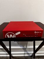 Front view showing the Firebox T55 branding, LED lights, and the red color of the security appliance.