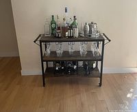 Front view of bar cart with bottles, glasses, and bar tools displayed showing glass racks, bottle racks, and overall structure