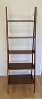 Front view of wooden bookshelf with five shelves and ladder style frame.