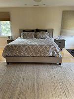 Front view of California King bed frame with upholstered headboard and bedding (not included).