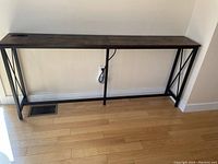 Full view of the charging station table showing wood grain laminate top and metal frame