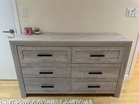 Front view of a wooden chest of drawers with six drawers, black handles, and light gray finish.