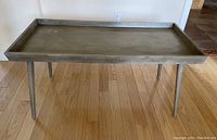 Rectangular wood grain laminate coffee table showing overall shape, four legs, and tray-style edge.