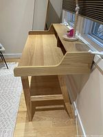 Side angle of the Safavieh wooden desk showing the light wood finish and raised shelf design.