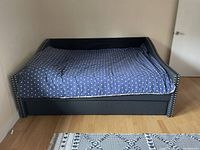 Front view of navy blue fabric daybed with nailhead trim and bedding