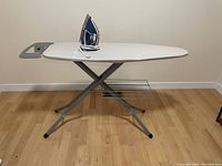 Side profile of ironing board showing iron resting in board holder and metal rack under the board.
