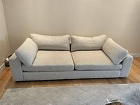 Front view of the off white 2-seat sofa showing cushions and upholstery.