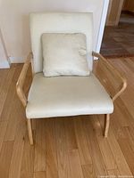 Front view of white fabric armchair showing wooden arms and cushion on seat.