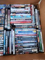 Box of assorted DVD movies showing a variety of titles including Antwone Fisher, Ghost Rider, Sweet November, Eminem 3, American Beauty, Seabiscuit, and Star Trek The Next Generation season 1.