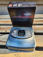 Handheld console seated on closed protective case with original box behind