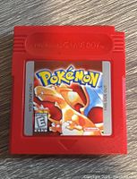 Front view showing label with Pokémon Red and Charizard artwork on red Game Boy cartridge.