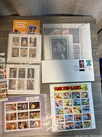 Photo showing several stamp sheets including Marilyn Monroe, Antique Portraits, Old Master Paintings, Comic Strip Classics, and an introductory booklet.