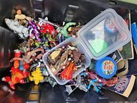 Top view of the black tote containing assorted vintage action figures from multiple franchises, some figures are loose, others in a clear plastic container.