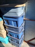 Stack of six blue Rubbermaid Roughneck storage totes with gray lids.