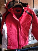 Front view of AlpineTek winter coat held on a hanger, showing red and white color scheme and black accents.