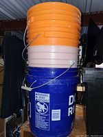 Stack of orange, pink and blue plastic buckets in a storage area