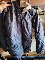 Black Columbia jacket held up for display showing front with zip closure and pockets
