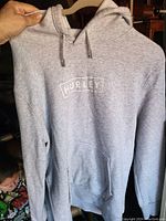 Front view of light gray Hurley hoodie sweater showing curved white Hurley logo and kangaroo pocket.