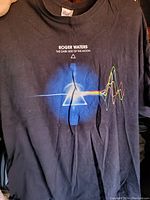 Front side of black Roger Waters shirt showing The Dark Side of the Moon prism graphic.