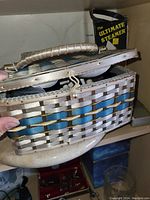 Closed woven basket sewing kit box with handle and clasp held open showing woven texture and blue trim.