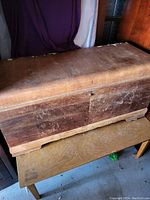 Side view of solid wooden chest with worn surface and aged lock on front.