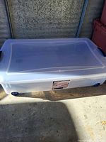 Photo of Sterilight plastic storage tote in a garage setting showing the full closed bin with lid, handles, and wheels visible.